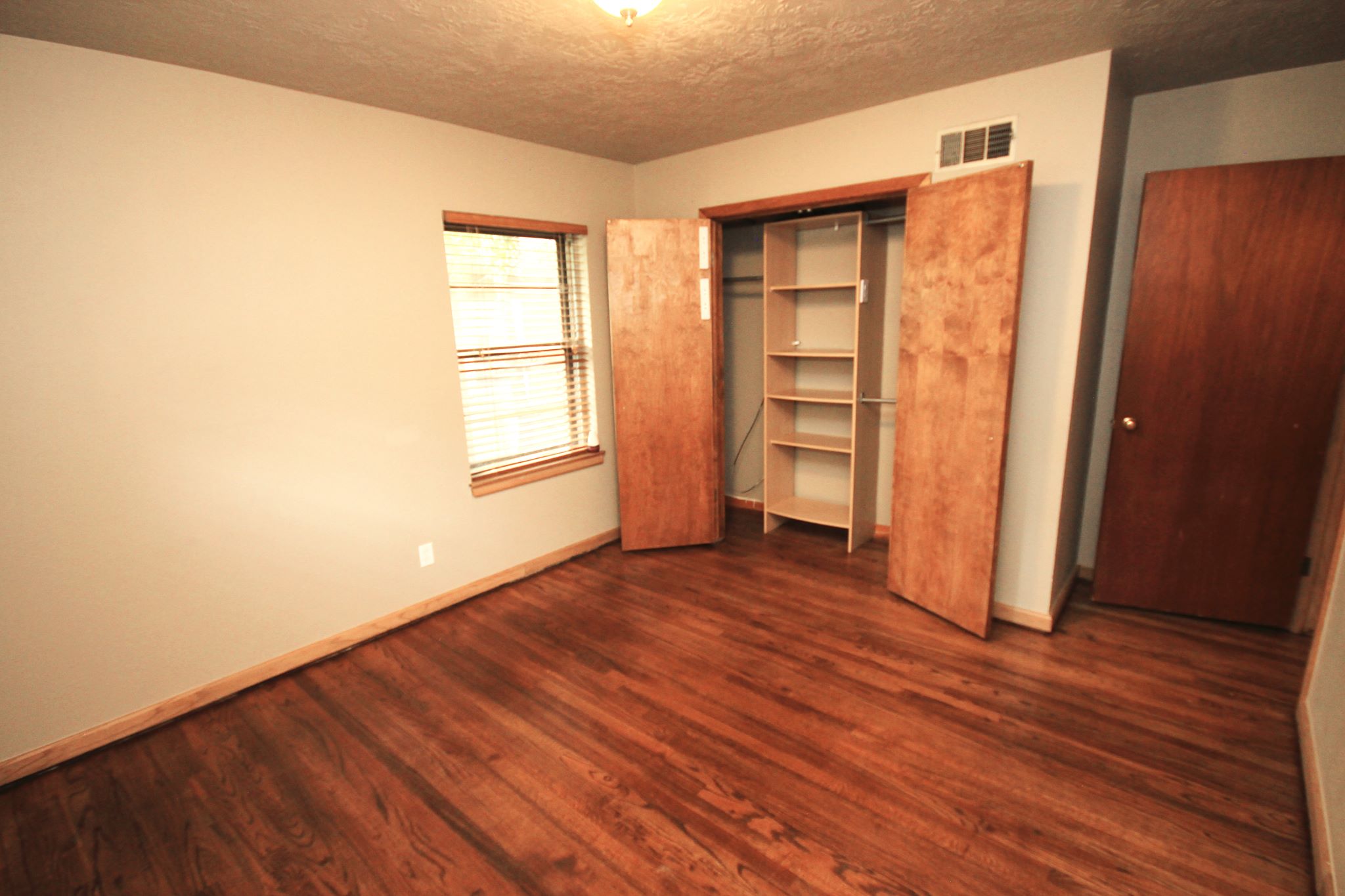 A bedroom with wooden floors and two large closets.