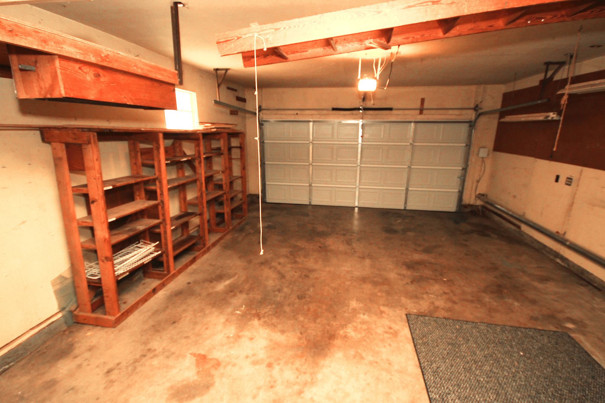A garage with two shelves and a rug.