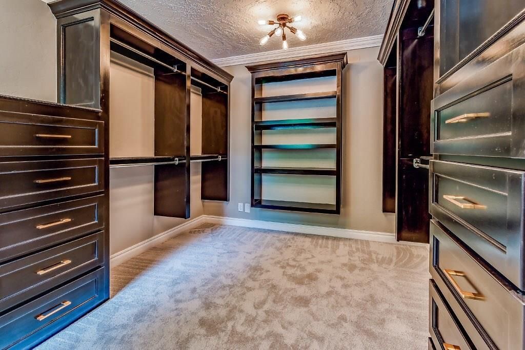 A large walk in closet with many shelves.