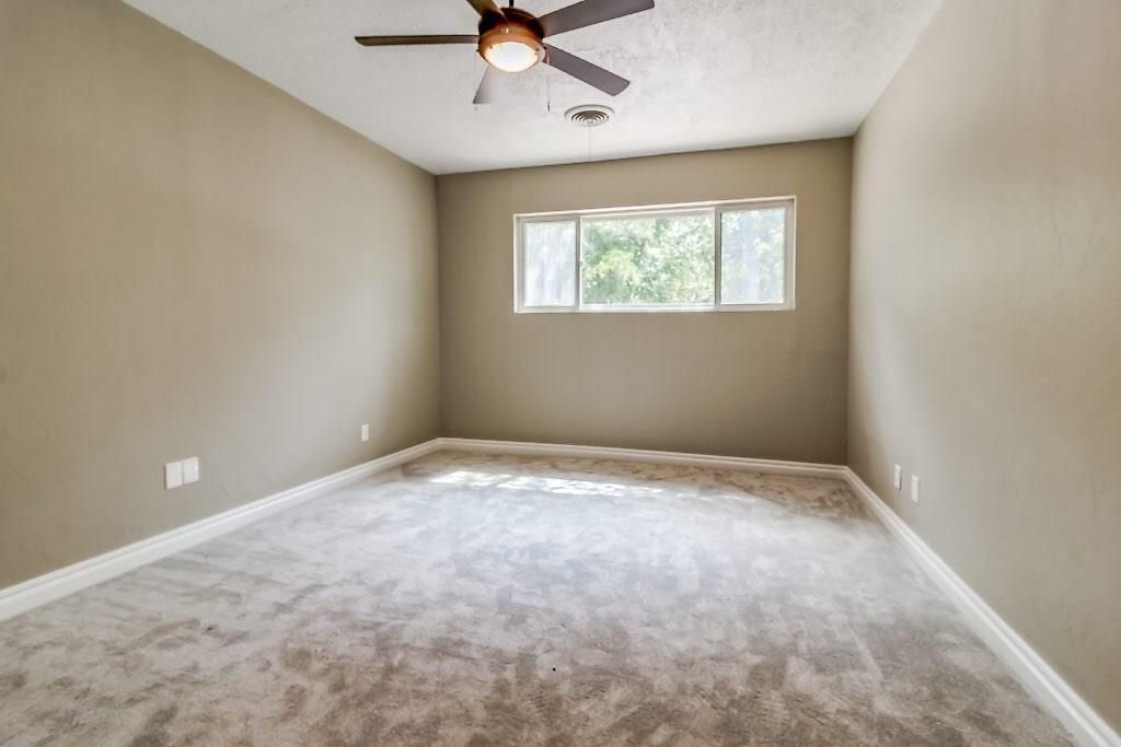 A bedroom with a ceiling fan and carpet.