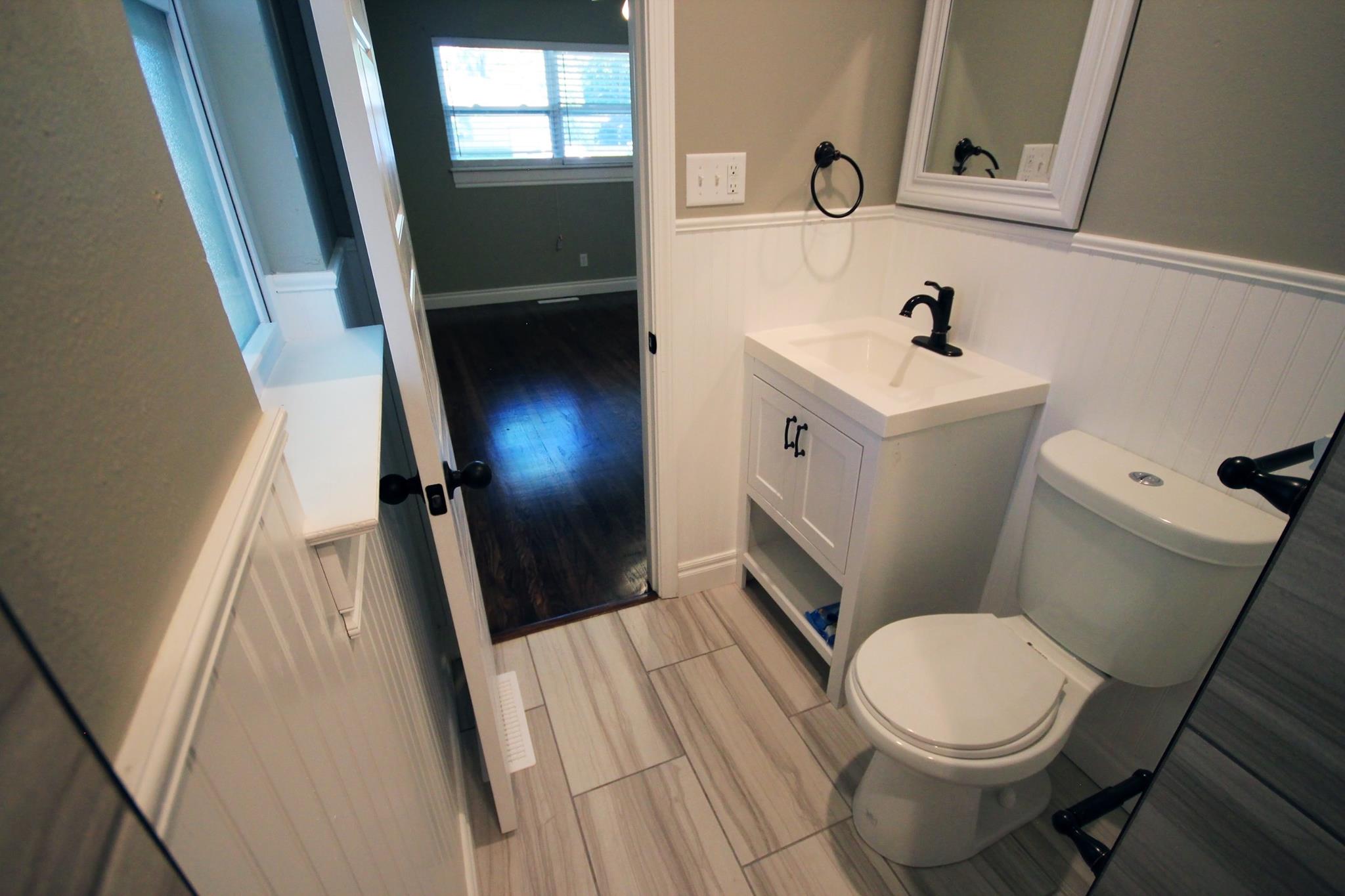 A bathroom with white tile floors and walls.