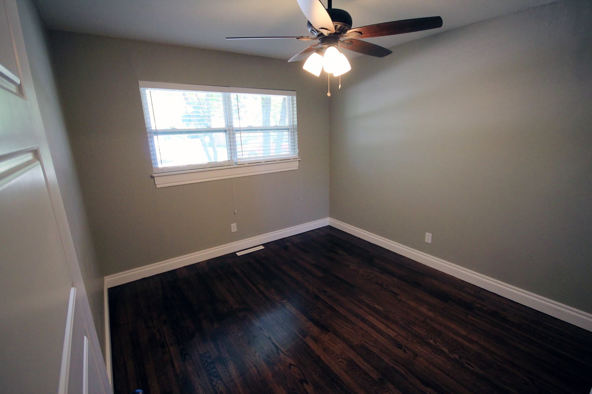 A bedroom with hard wood floors and ceiling fan.
