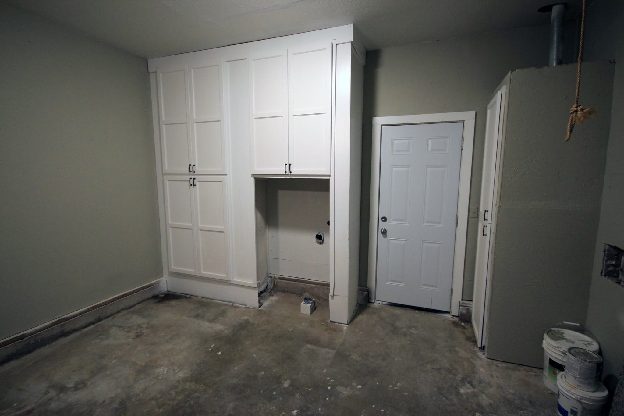 A room with two white cabinets and a door.