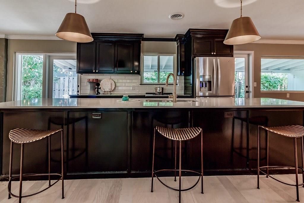 A kitchen with dark cabinets and white counter tops.