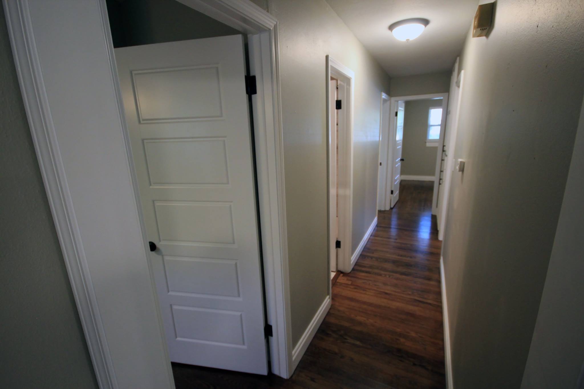 A hallway with two doors and wooden floors.
